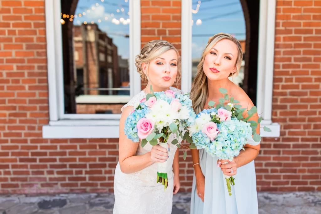 Wedding venue in Chattanooga showcasing 2 girls in dresses holding flowers standing outside of a red brick church.