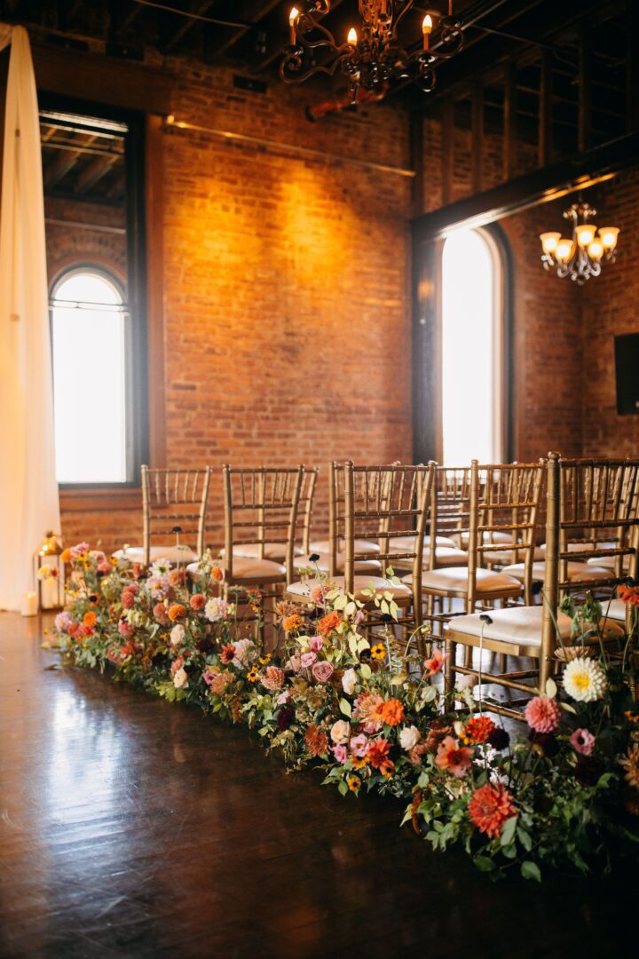 Wedding venue in Chattanooga showcasing golden chairs and white drapes facing a brick wall with large windows and chandeliers