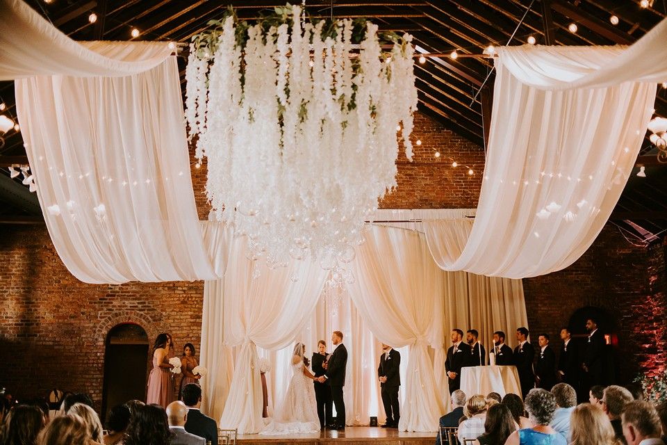 Wedding packages in chattanooga showcasing married couple standing on a stage with white drapes hanging from the ceiling.