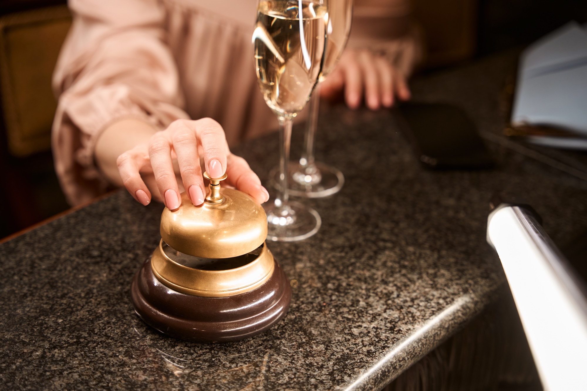 Female hand ringing golden bell for service at counter desk in the bar Wedding packages in chattanooga showcasing a bride and groom standing on stage preparing to be married.