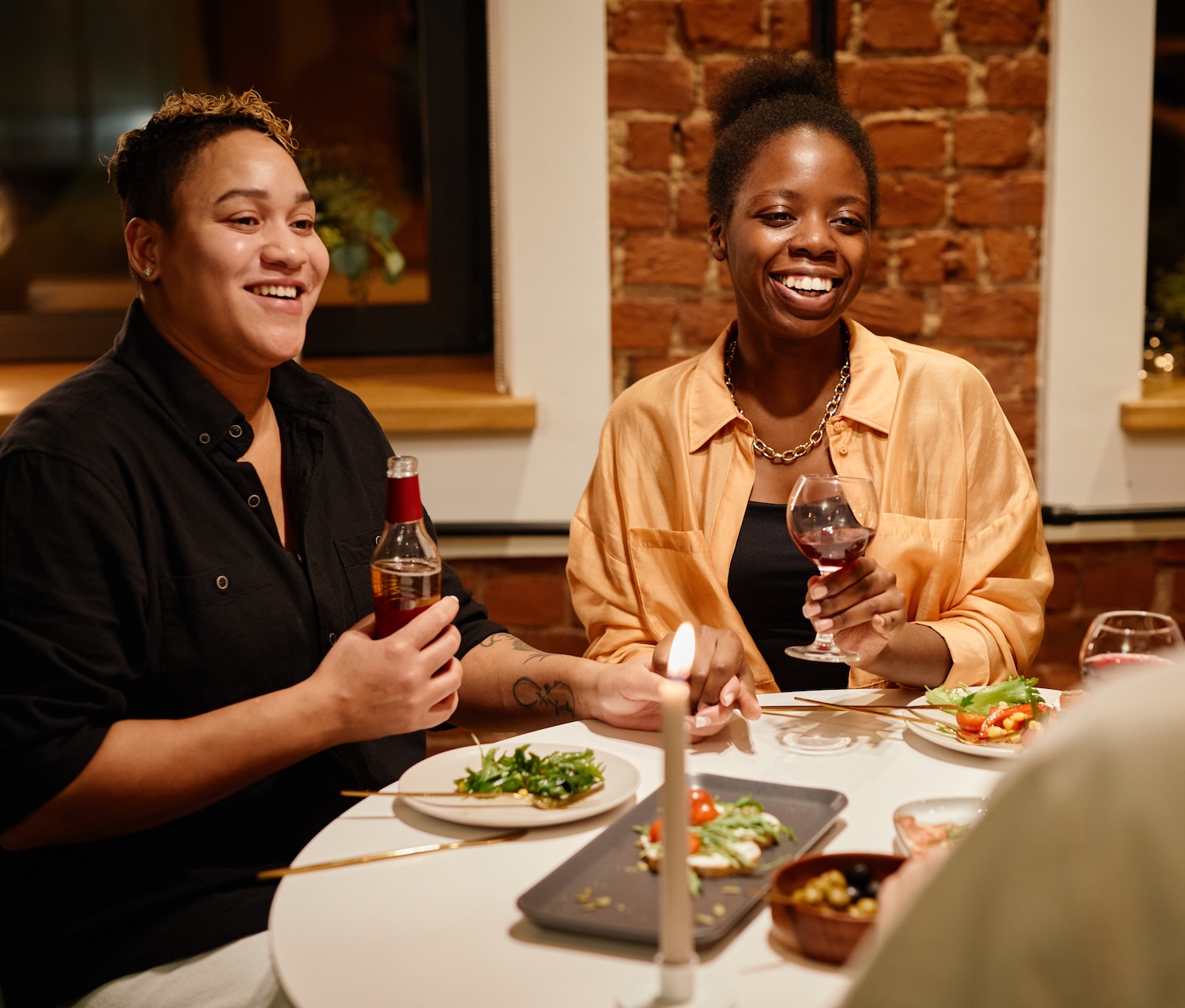 Happy young lesbian couple with alcoholic drinks sitting by served table Wedding packages in chattanooga showcasing a newly married couple walking down the isle.