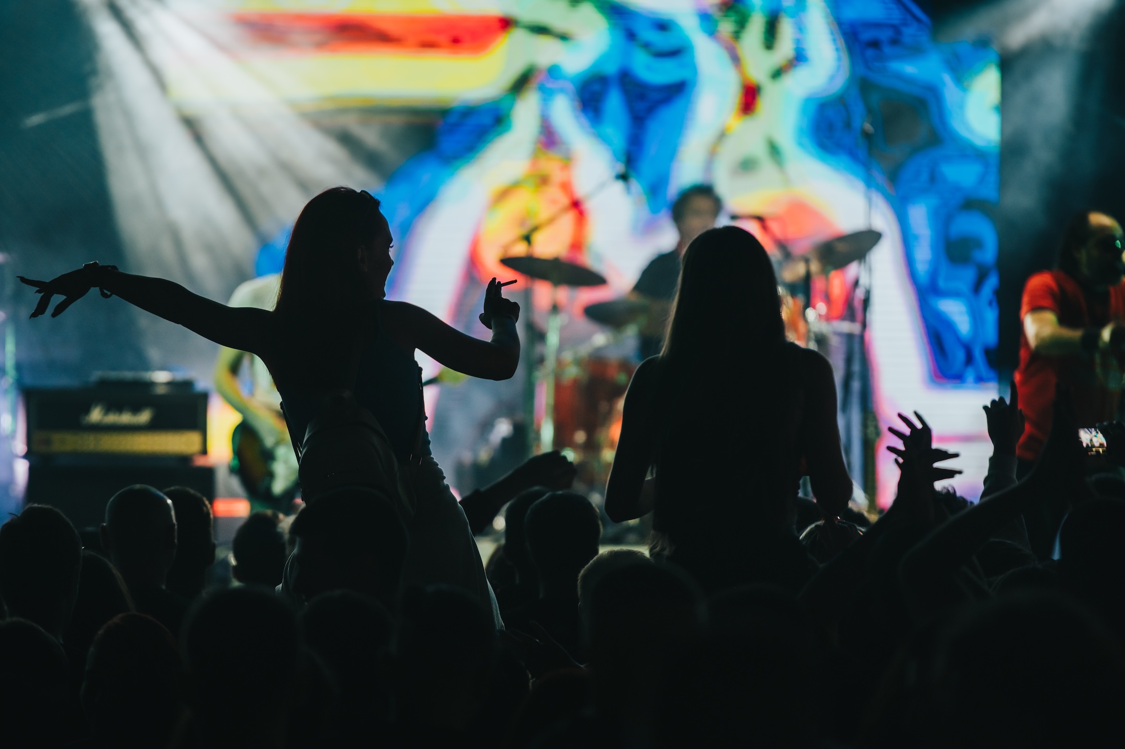 Two woman in the crowd at a music festival Wedding packages in chattanooga showcasing a bride and groom standing on stage preparing to be married.